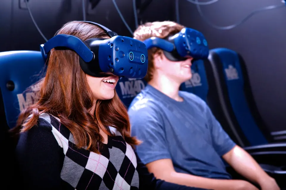 Two travelers wearing VR headsets in blue motion seats at Truth Traveler Branson